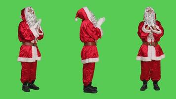 Joyful character applauding on camera, cheering for something and clapping hands on greenscreen backdrop. Santa claus being happy with standing ovation gesture, traditional red costume. photo