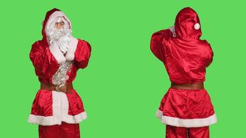 Impatient santa claus in suit checking time on wristwatch while he stands over greenscreen backdrop. Young adult dressed in festive winter character costume waiting for something, xmas spirit. photo