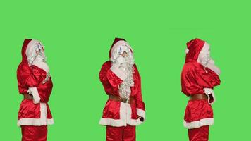 Thoughtful man in santa claus suit thinking about list of gifts, brainstorming session for presents ideas. Saint nick character with hat and white beard being pensive over greenscreen backdrop. photo