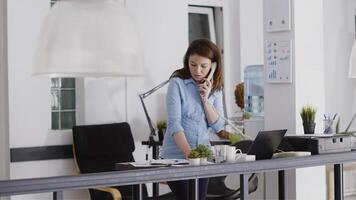Executive assistant answering landline phone call in startup office, working on business development. Professional manager using office cord telephone to have remote chat at desk. photo