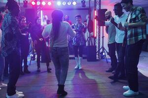 diverso mujer bailando en pista de baile mientras asistiendo disco fiesta en Club nocturno. grupo de clubbers disfrutando noche fuera y teniendo divertido a discoteca en club a la vida nocturna reunión foto