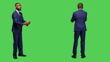 Young adult in suit having symphony concert at opera, conducting choir music posing over green screen backdrop. Optimistic conductor working as choirmaster having musical event in studio. photo