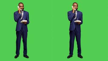 Confident employee answering landline phone call, having remote conversation on office telephone line with cord in studio. Male manager talking on phone, full body green screen. photo