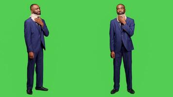 Injured businessman wearing suit and cervical neck collar standing over full body green screen. Young man employee being in pain after injury, medical brace for fracture in studio. photo