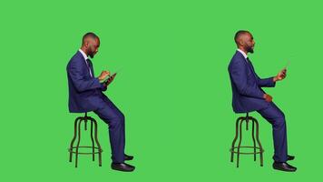 Male employee browsing online and using videocall on digital tablet, attending business meeting teleconference. Young adult in formal suit working with modern device over greenscreen. photo