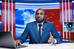 Journalist transmissing live content on media segment, using latest headlines to create reportage newscast for television network. Presenter host reading informations in newsroom. photo