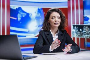 Newscaster discussing on live program, broadcasting latest news reports to create essential television content. Woman journalist working on media segment, reading daily news headlines worldwide. photo