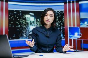 Talk show host presenting daily news and latest events on live television channel to cover worldwide topics, tv reportage. Asian woman discussing celebrity scandals in newsroom studio. photo
