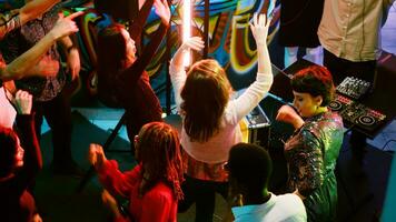 grupo de joven personas ir de fiesta a club, teniendo divertido en danza piso y baile. alegre personas disfrutando noche fuera con moderno música y amigos, miedoso entretenimiento. Mano disparo. foto