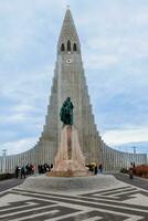 Hallgrimskirkja cathedral circa March 2023 with majestic concrete statue of explorer Leif Erikson, holy sacred monument. Spectacular tall building indicating lutheran faith and religion. photo