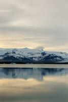 hielo cubierto laderas y grande escandinavo lago en ártico región de Islandia. invierno mundo maravilloso maravilloso ruta con increíble puesta del sol ligero durante dorado hora, polar aventura. foto