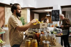 Man in zero waste store taking time to analyze fruits, making sure they are locally grown. Customer thoroughly checking local supermarket food items are ethically sourced photo