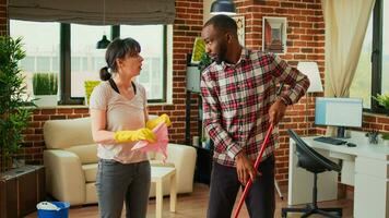 Diverse people vacuuming floors and cleaning furniture on shelves, sweeping mess or dirt with tools. Man and woman using vacuum cleaner with suction, gloves and rags to clean household. photo