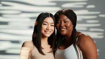 Cheerful unique girls advertising body confidence, embracing eachother in studio and showing self love. Beautiful diverse women with different body types and skintones, bodycare. photo