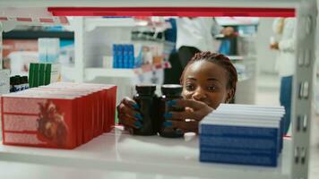 Woman pharmacist arranging medicaments on shelves, helping customers to find right medicine and treatment. Young adult putting vitamins and bottles of pills, pharmacy store. Close up. photo