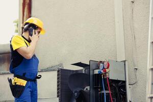 Certified engineer on the phone with client after finishing air conditioner maintenance check up. Licensed electrician calling customer to inform him about electrical issues found in hvac system photo