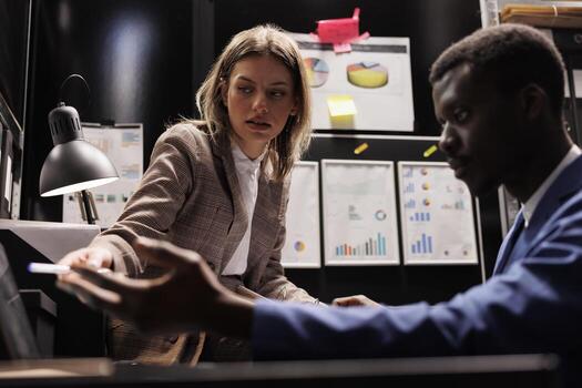 Diverse team discussing criminology report, working overtime at missing person case in arhive room. Private detectives searching new evidence trying to catch potential suspect photo