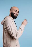 Smiling arab man inviting with arm gesture and looking at camera with cheerful facial expression. Happy arabian person welcoming to join, asking to come over studio portrait photo