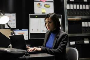 Professional asian accountant checking administrative analytical data in cabinet room office surrounded by accountancy statistic reports. Businesswoman in file storage room photo