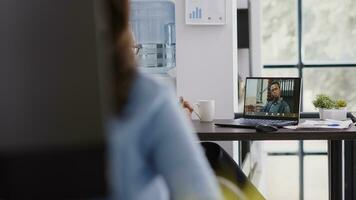 Young person attending business meeting videocall in startup coworking space, using online teleconference chat. Female assistant talking to people on remote video conference, telework research. photo