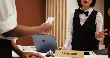 Asian receptionist offering african american business partners on work trip room access card key after finalizing check in. Tourists finishing booking process, close up dolly out shot photo