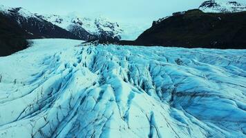 aéreo ver de masivo glaciar tapas en nórdico escenario, hermosa grande vatnajokull hielo bloques en Islandia. azul icebergs y glacial rocas cerca congelado lago y Nevado montañas. lento movimiento. foto