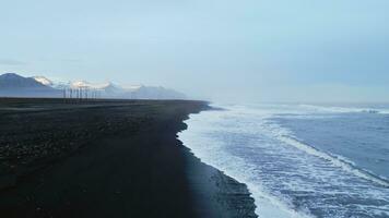 Drone shot of atlantic ocean with black sand beach in icelandic scenery, fantastic nordic landscape with coastline in iceland. Arctic country with majestic nature and scenic route. Slow motion. photo