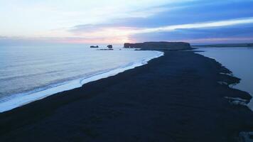 Aerial view of black sand beach with mountains and big stones in iceland, beautiful natural scenery on reynisfjara beach. Icelandic landscape with atlantic ocean on coastline. Slow motion. photo