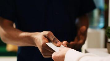 Male tourist receiving room key card for accommodation access after check in at front desk lobby. Seaside resort tourist registering at reception with hotel employee. Close up. Handheld shot. photo