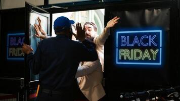 Crazy obsessed shoppers push front door open to shop on black friday, fighting with security officer. Aggressive group of clients breaking into clothing store, rushing to find clothes on sale. photo