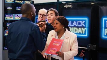 Black Friday shopping madness. Group of mad diverse clients push security guard to enter first into shopping center. Bargain hunters going crazy to get best deals, seasonal discounts. photo