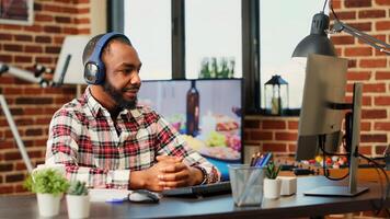 Smiling person watching suspenseful online thriller movie, enjoying himself in stylish apartment. Relaxed man wearing headphones, hooked by streaming service tv show on computer, close up photo