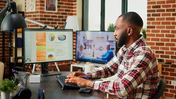 Remote employee checking online business analytics statistical data charts while working from home in stylish apartment. Teleworker optimizing market performance indicators with tv as background noise photo