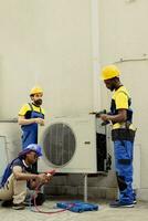 Qualified electricians installing condenser for client after replacing broken unit. Professional workers enlisted to optimize new HVAC system's performance, ensuring it operates at maximum capacity photo