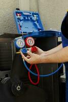 conocedor ingeniero calibrando manómetros durante encargado al aire libre hvac sistema supervisión. sazonado mecánico mirando para bajo refrigerante niveles en aire acondicionador enfriamiento sistema foto