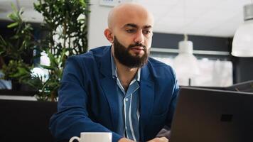 Businessman solving startup problems with laptop and archived documents, looking at annual statistics report to find issue. Young analyst reviewing papers, executive strategy plan. photo