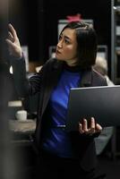 Detective woman in criminology agency cabinet room looking for criminal case file folders on cabinet shelves. Asian private investigator in archival storage repository office photo