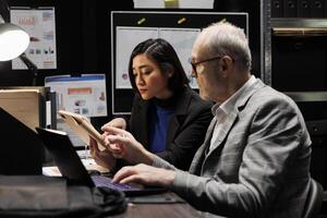 Elderly business manager and consultant employee brainstorming accountancy market data analysis paperwork. Teamwork in archival repository office filled with statistic graphic charts photo