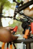 Detailed shot of female african american pair of hands holding screwdriver from toolkit for bicycle maintenance. Skilled individual examining and arranging specialized tools. photo