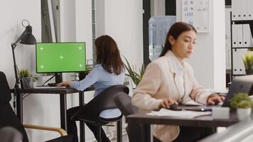 Business manager analyzing greenscreen display on pc, chekcing isolated copyspace on computer in coworking space. Employee using blank mockup template on screen, agency office. photo