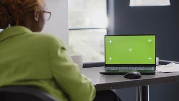 Business manager looking at pc with green screen, using isolated mockup display in agency office. Corporate employee checking chroma key copyspace template at executive startup job. photo