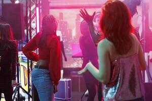 People partying at disco gathering and enjoying nightlife activity in nightclub. Diverse men and women dancing and celebrating while moving to modern music rhythm in club photo