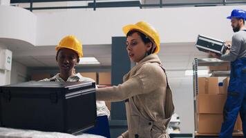 Woman employee looking at list of goods in boxes, working with colleagues to send merchandise for stock distribution. Female supervisor in overalls checking products order for shipment. photo