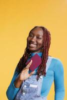 sonriente niña participación de viaje pasaporte en estudio, utilizando internacional documentación antes de embarque vuelo. joven mujer teniendo identificación pasar para vacaciones viaje, fin de semana escapar. foto