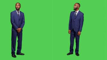 Male entrepreneur having amazed and surprised reaction, feeling stylish in business office suit over full body greenscreen. Corporate employee in awe seeing something in studio. photo