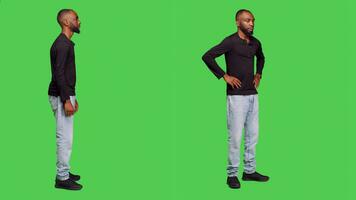 African american man being impatient waiting in studio, thinking about something on camera. Male person brainstorming ideas with patience, standing over full body green screen. photo