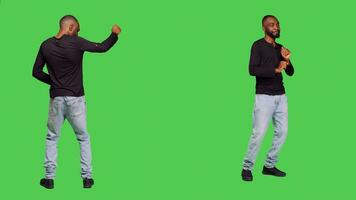 Joyful smiling man doing dance moves acting funny standing over full body green screen backdrop. Young adult being silly and dancing, feeling funky on camera. Leisure activity. photo