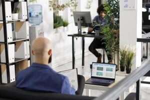 Businessman using laptop to analyze stock market data in corporate office. Executive manager checking company profit and revenue with financial infographics and charts on screen photo