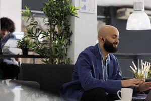 Project manager using video conference app on laptop to manage team remotely while working in business office. Entrepreneur talking in online meeting while sitting on couch at coworking space photo