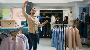 Store manager working with augmented reality hologram in shopping center, looking at modern trendy clothes on hangers. Retail worker using artificial intelligence in boutique, small business. photo